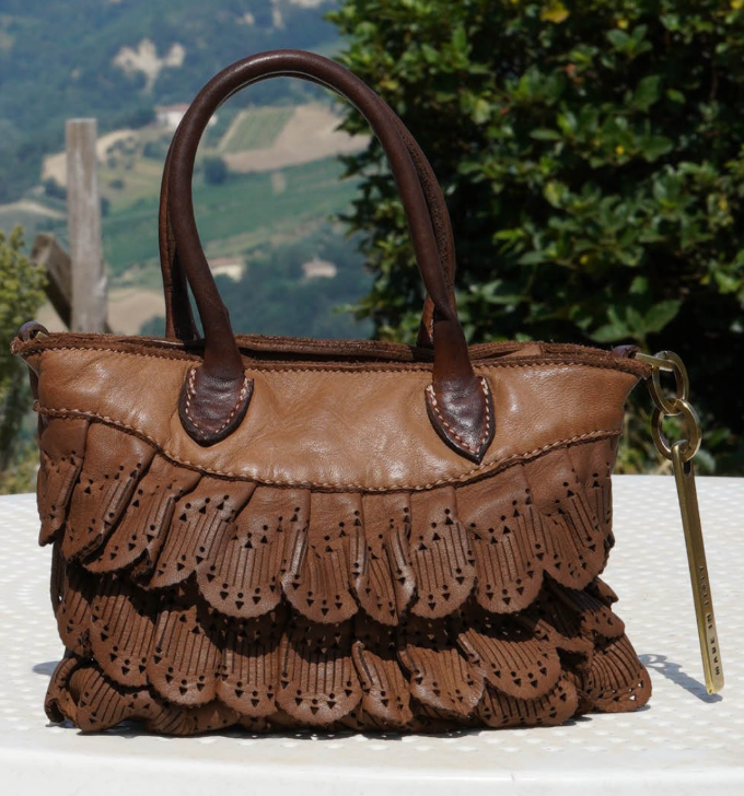 Artisanal brown leather handbag from Caterina Lucchi featuring intricate scalloped and perforated detailing with layered fringe elements. 